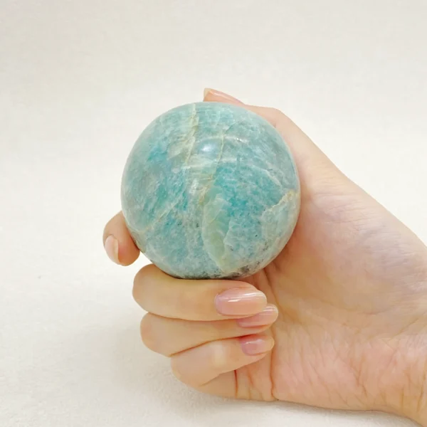 The Amazonite Sphere supports heartfelt communication, emotional balance, and gentle transformation. With its soothing blue-green tones, it encourages honest self-expression while easing fear around change. Resting on its round base, this sphere radiates calm confidence, helping you move forward with clarity and trust.