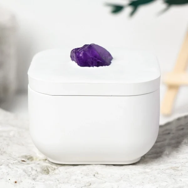 A luminous Amethyst Crystal Candle set within a raw gypsum holder and infused with the refined aroma of Rose of No Man’s Land. This handcrafted piece pairs natural amethyst with a clean-burning scented soy candle, creating a romantic yet grounding atmosphere for reflection, calm, and elevated home décor.