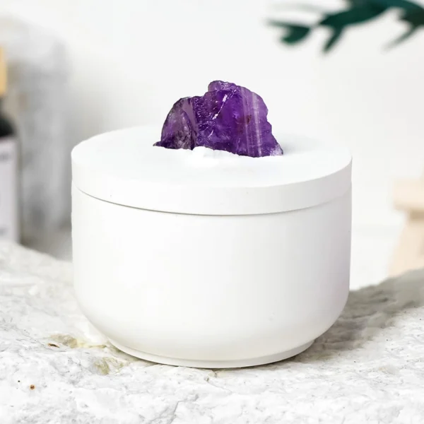 A luminous Amethyst Candle set within a raw crystal gypsum holder, paired with a delicate gardenia fragrance. This handcrafted piece blends natural amethyst energy with a clean-burning scented soy candle, creating a serene atmosphere for relaxation, intuition, and refined home décor.